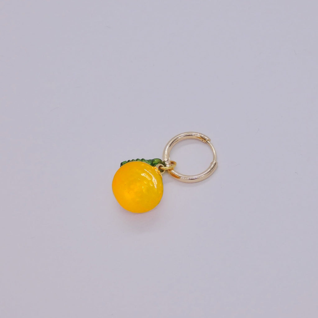 Yellow round charm with a gold ring on a light gray background